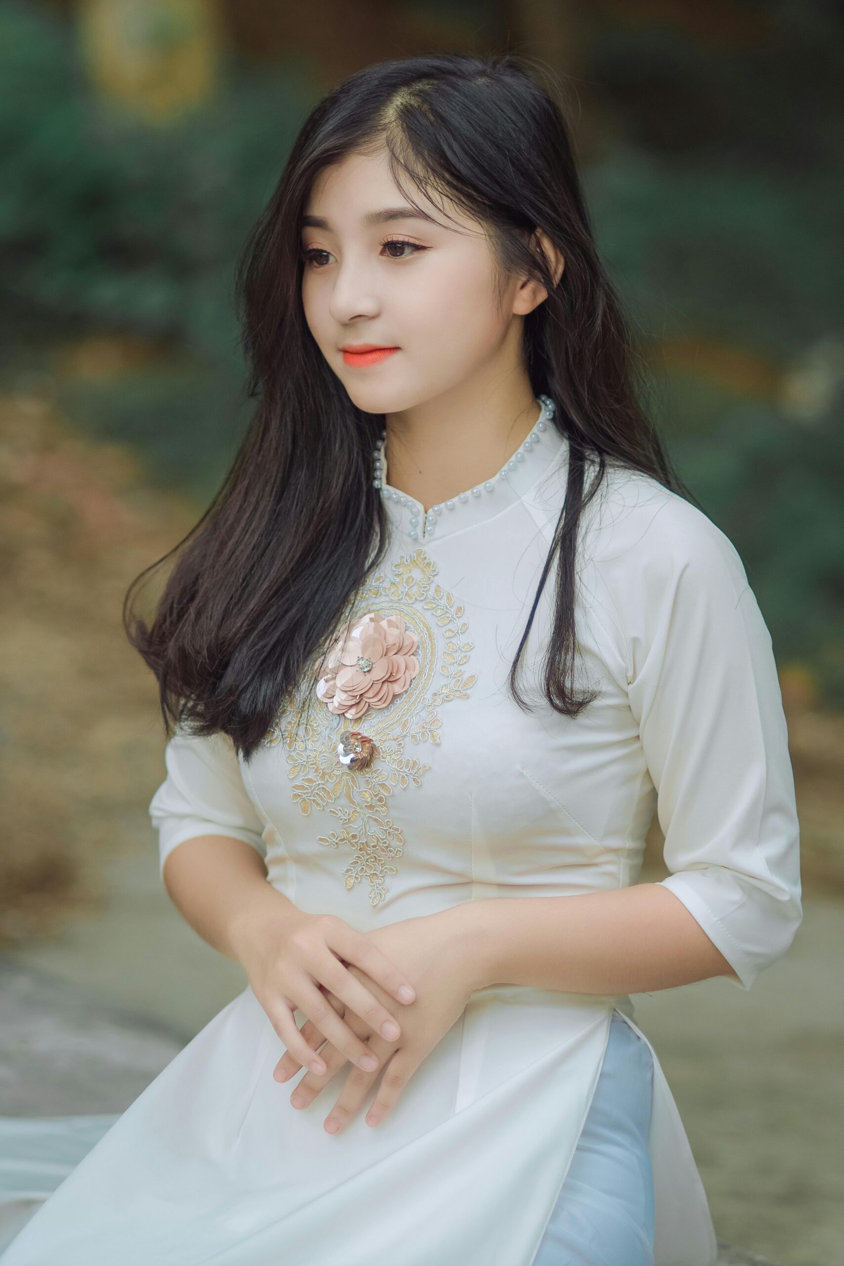 Beautiful young woman in a traditional dress posing outdoors, showcasing a serene and elegant fashion style.
